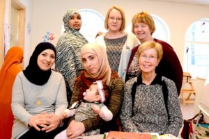 Bild på medverkande i projektet. Tre kvinnor som står upp, tre kvinnor och ett barn sitter framför dem. 