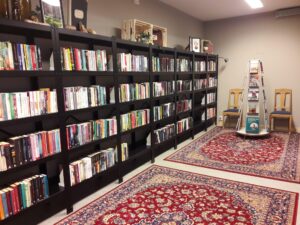 Foto på biblioteket i Vaggeryds bibliotek. Svarta hyllor med böcker och röda mattor på golvet.